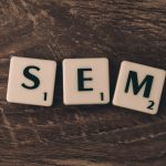 Wooden background with letter tiles spelling SEM, representing search engine marketing. — The Future of Industry: Trends and