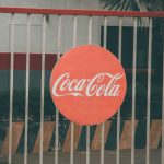 Coca-Cola logo prominently displayed on outdoor fence, urban setting. — The Role Of The Supreme Court In Shaping The Law.